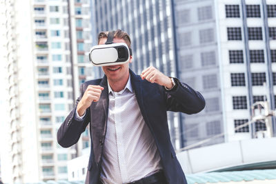 Man holding smart phone while standing on laptop