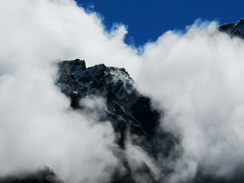 Low angle view of clouds over mountain against sky