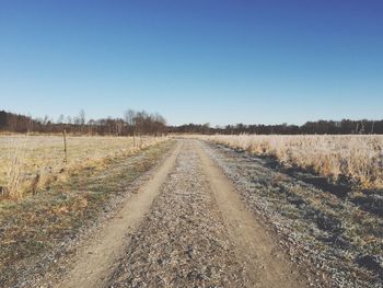 Empty road amidst landscape against clear blue sky