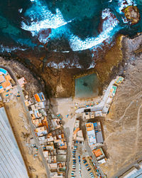 Breathtaking drone view of rooftops of buildings in settlement located on coast near blue sea