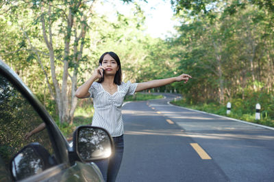 Portrait of a young woman with umbrella on road