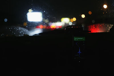 Illuminated city seen through wet windshield at night