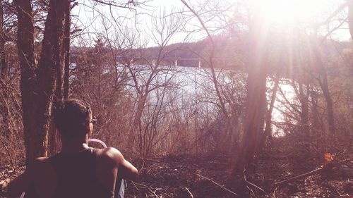 Rear view of woman sitting in forest