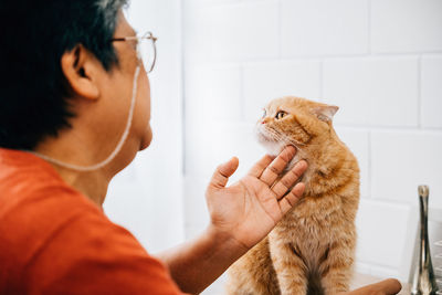 Side view of young woman holding cat