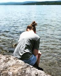 Rear view of woman sitting on rock