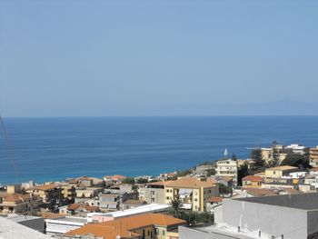 High angle view of townscape by sea against clear sky