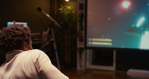 Rear view of woman looking through window