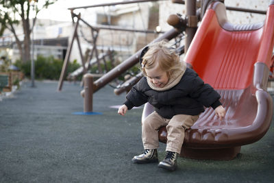 Cute girl sitting on slide at park