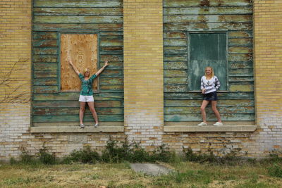 Full length of girls standing on old abandoned window