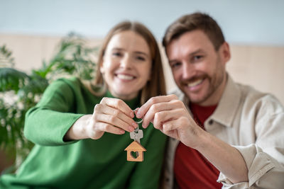 Joyful smiling couple showing keys of own new apartment, house, proud of buying own property