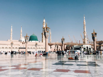 Crowd by mosque against sky