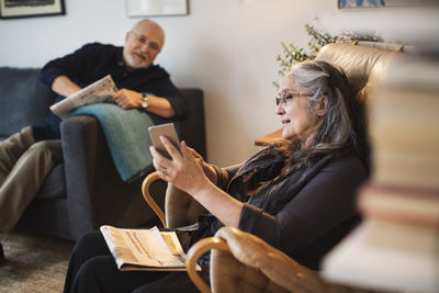 Senior woman showing mobile phone to man at home