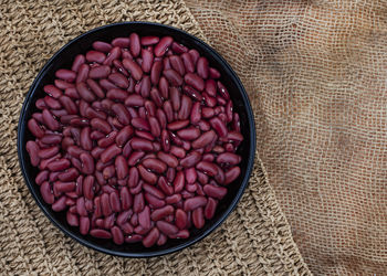 Bowl of raw uncooked red kidney beans on rustic surface