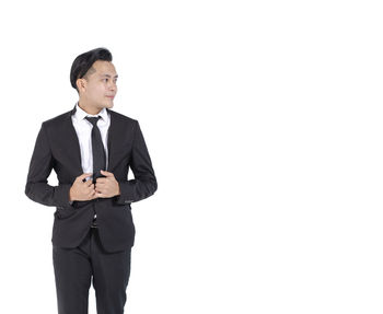 Young man looking away while standing against white background