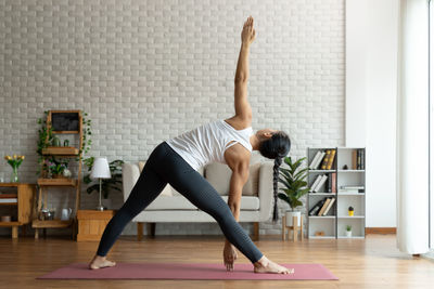 Young woman with arms raised on floor at home