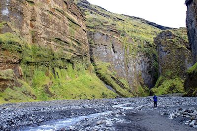 Man walking on road by cliff against sky