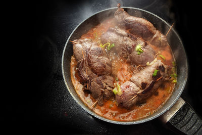 High angle view of meat in cooking pan on stove