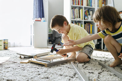 Playful brothers learning to assemble nightstand at home