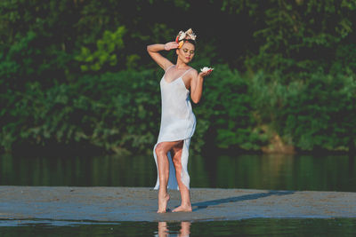 Full length of young woman standing by lake