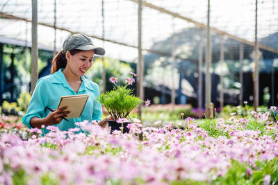 Woman looking at flowering plants in greenhouse