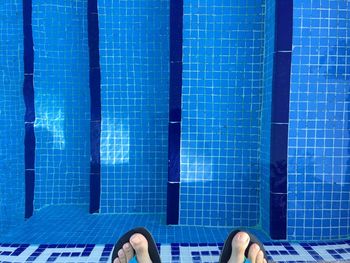 Low section of man standing by swimming pool