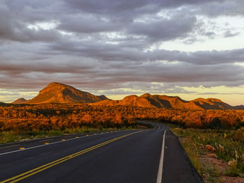 Empty road along landscape and mountains against sky