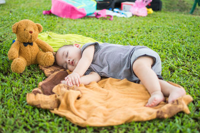 Cute boy sleeping with toy on field