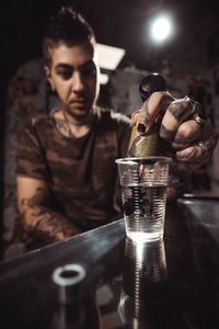 Close-up of man holding tattoo machine dipping in water