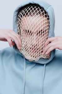 Young man wearing net on face while wearing hoodie