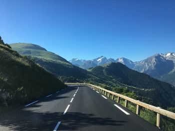 Road amidst mountains against clear blue sky