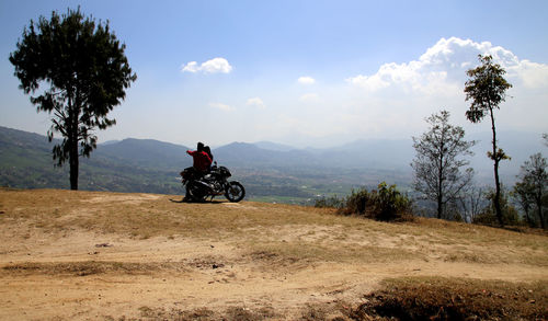 Man riding motorcycle on mountain against sky