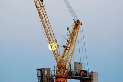 Low angle view of cranes at construction site against sky