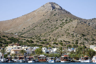 Boats moored in sea at elounda against mountain
