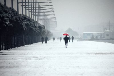Rear view of people walking on snow covered street