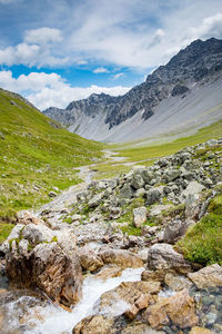 Scenic view of stream amidst mountains against sky