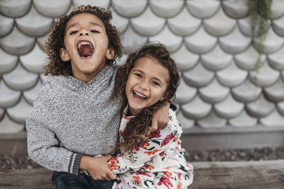 Cute siblings smiling and laughing while hugging