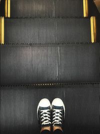 Low section of person standing on escalator