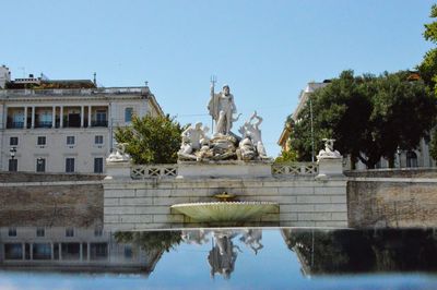 Statue by lake against clear sky