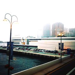 Bridge over river by buildings in city against clear sky