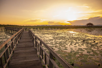 Pier over sea against sky during sunset