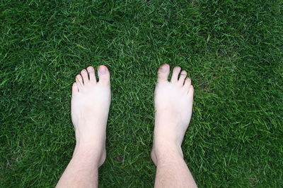 Low section of man standing on grassy field