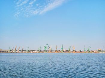 Cranes at harbor against blue sky