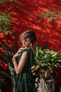 Portrait of a young woman in a green dress against a red wall