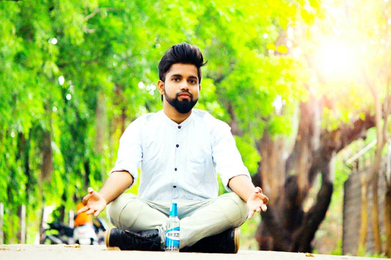 YOUNG MAN SITTING IN PARK