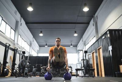 Male athlete exercising with kettle bell in gym