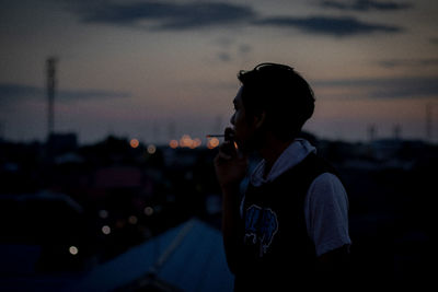 Man looking at city against sky during sunset