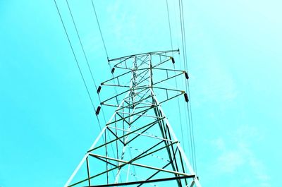 Low angle view of electricity pylon against clear blue sky