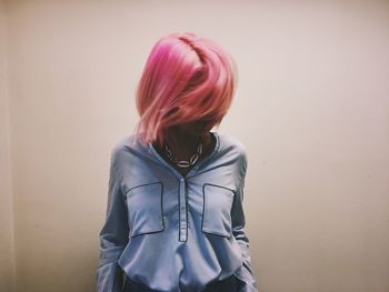 Young woman with pink hair against white background