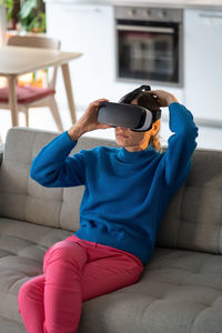 Young woman puts on vr glasses for first time and prepares to play interesting games at home