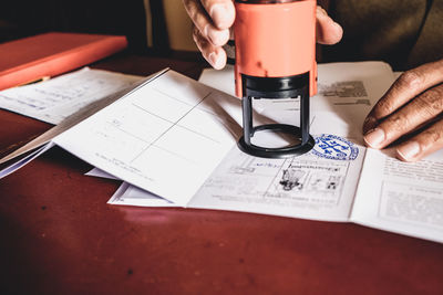 Close-up of man stamping documents on desk in office